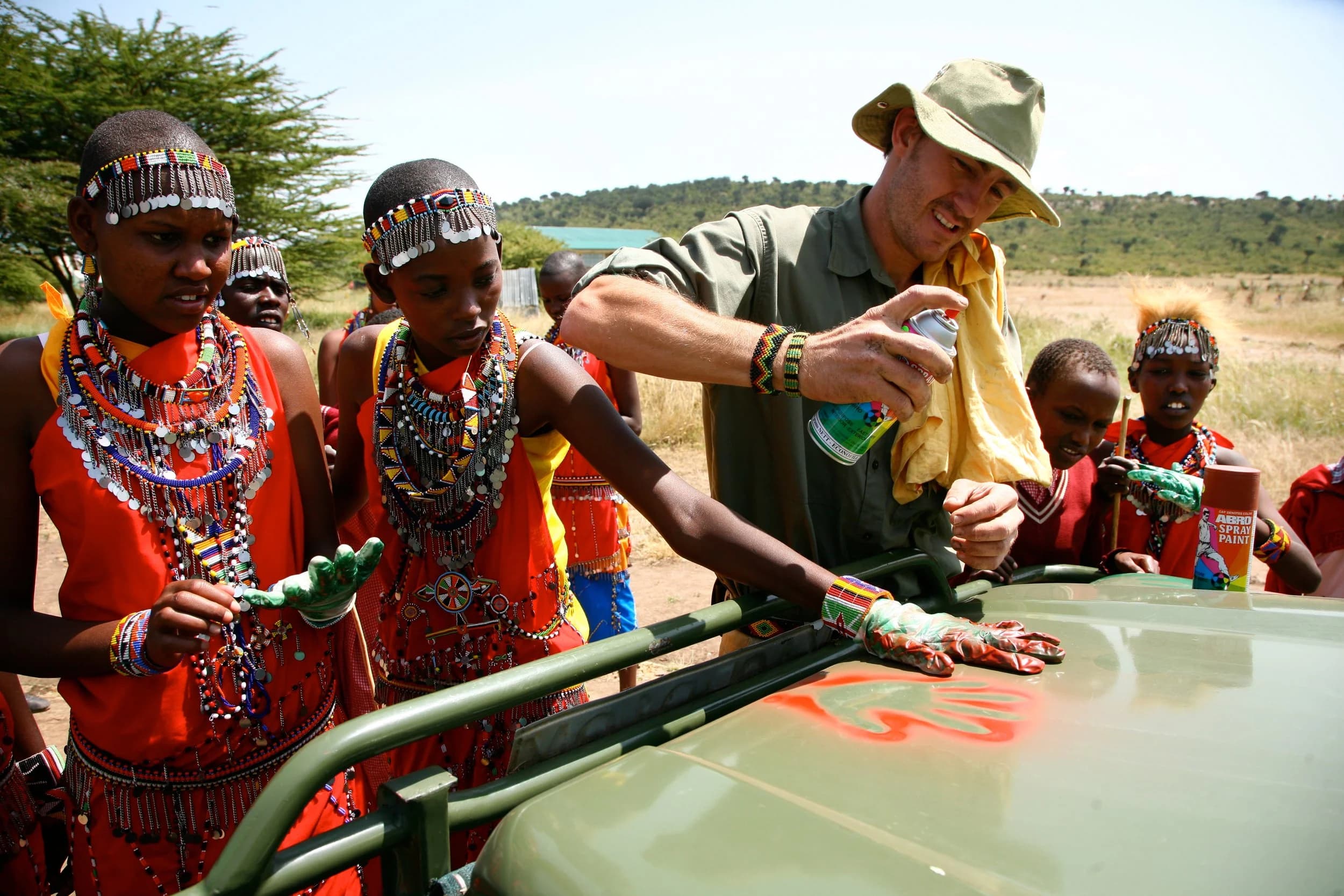 Maasai children from a school environmental club sign their commitment to the environment with painted handprints on a safari vehicle