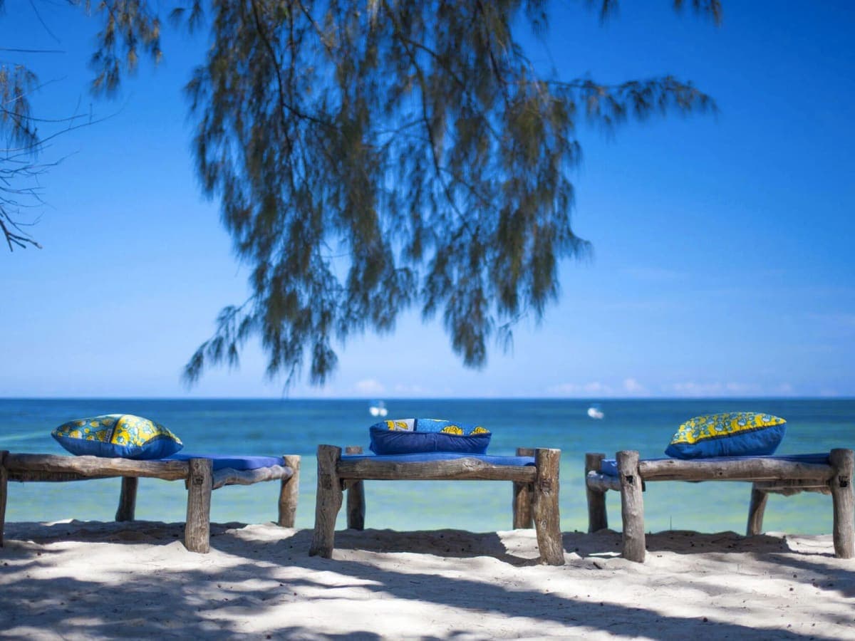 Wooden benches with blue cushions on the sand facing the Indian Ocean at Kinondo Kwetu