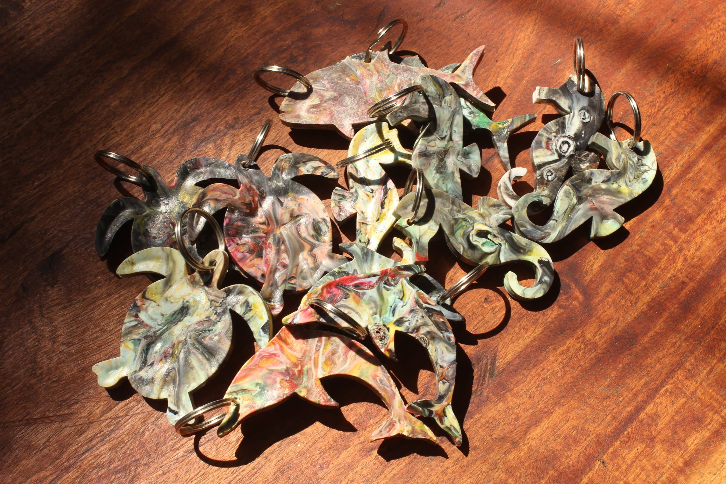 Colourful marbled leaf-shaped earrings scattered on a sunlit wooden surface